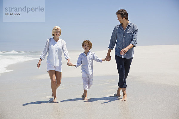 Ein Paar  das mit seinem Sohn am Strand spazieren geht.