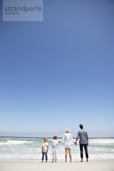 Familie mit Blick auf das Meer vom Strand aus