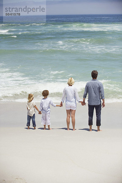 Paar mit ihren Kindern am Strand stehend