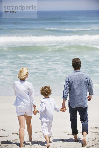Paar mit ihrem Sohn  der am Strand spazieren geht.