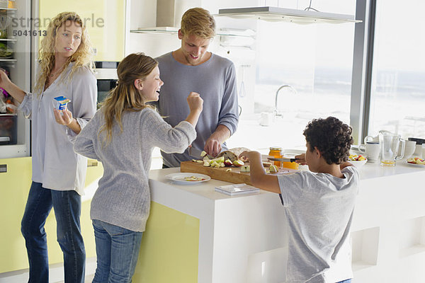 Paar mit ihren beiden Kindern beim Zubereiten von Essen in einer häuslichen Küche
