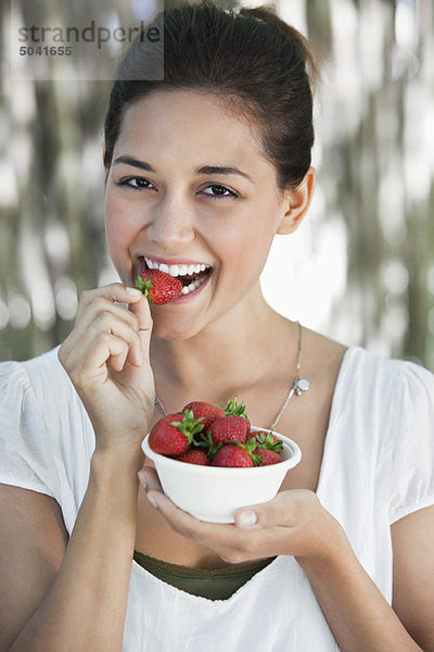 Porträt einer jungen Frau beim Erdbeeressen