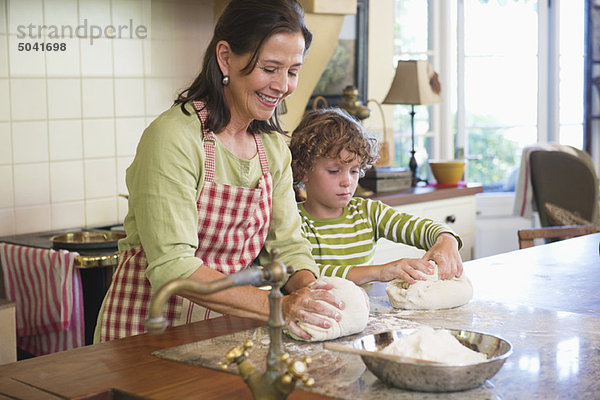Großmutter und kleiner Junge beim Teigkneten in der Küche