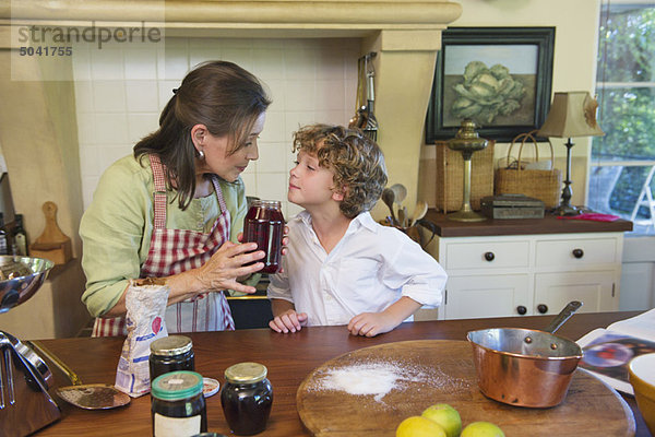 Großmutter und kleiner Junge riechenden Honig in der Küche