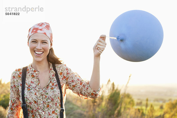 Schöne Frau spielt mit einem Ballon und lächelt.
