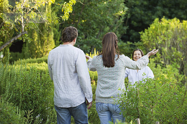 Ein reifes Paar  das in einem Garten auf seine Mutter zugeht.