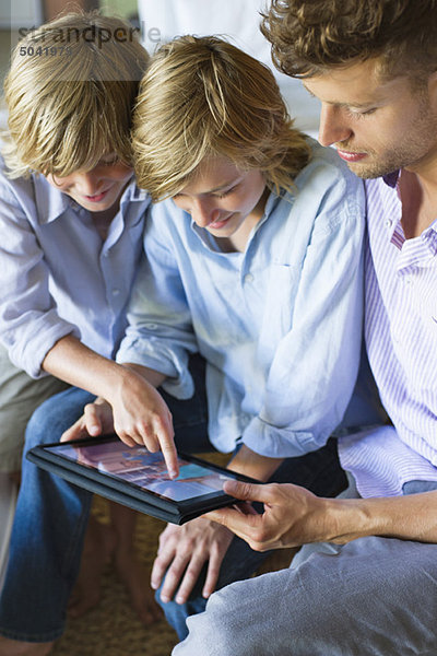 Mann und zwei kleiner Junge beim Betrachten des digitalen Tabletts