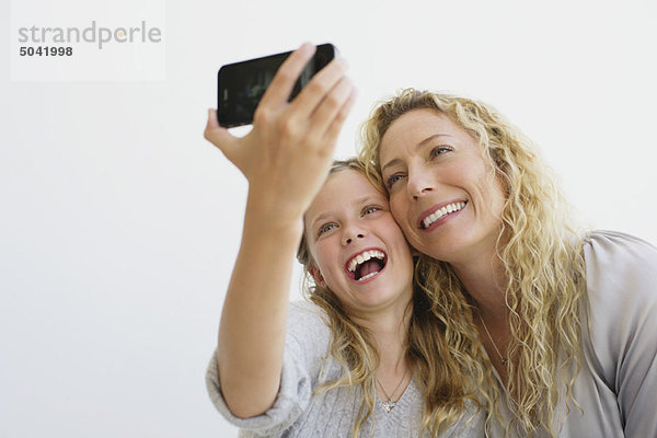 Mädchen mit ihrer Mutter beim Fotografieren mit dem Handy