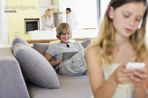 Teenager-Junge mit einem digitalen Tablett auf der Couch