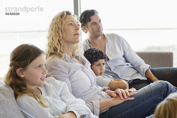 Familie mit drei Kindern auf einer Couch sitzend