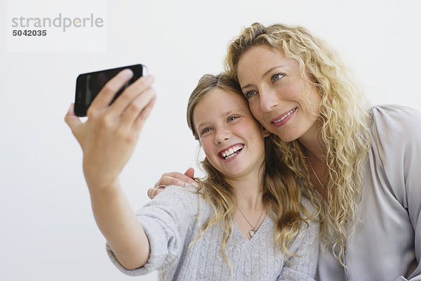Mädchen mit ihrer Mutter beim Fotografieren mit dem Handy