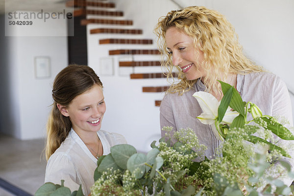 Mittlere erwachsene Frau und ihre Tochter berühren Blätter und lächeln
