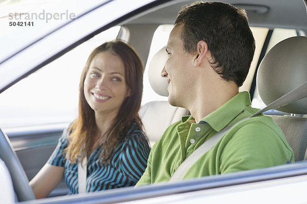 Glückliches Paar  das sich beim Autofahren ansieht