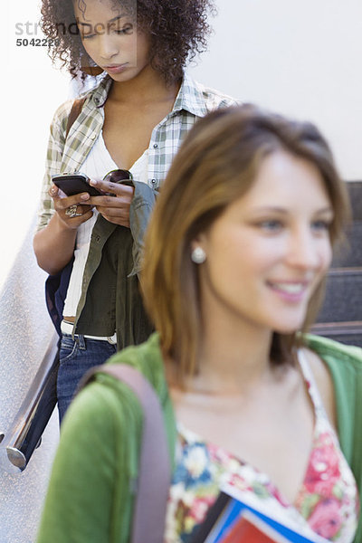 Nahaufnahme einer Studentin mit afroamerikanischer Frau über Handy im Hintergrund
