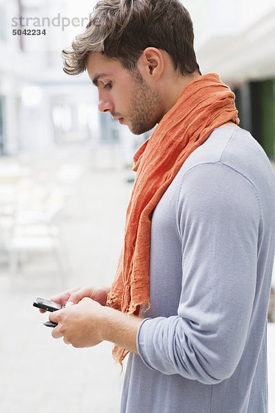 Seitenprofil eines jungen Mannes mit dem Handy