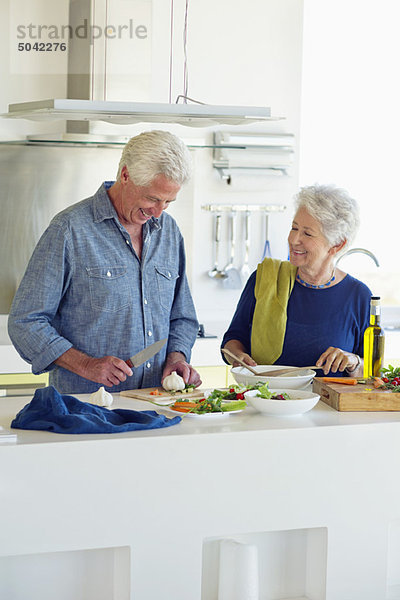 Seniorenpaar bei der Zubereitung von Speisen in der heimischen Küche