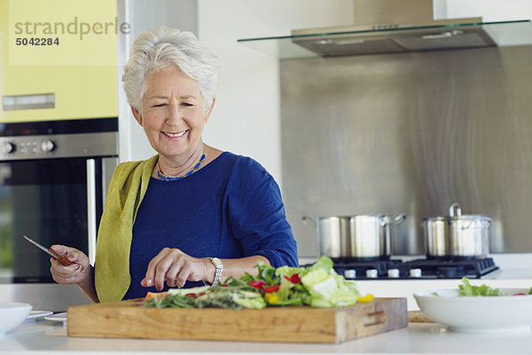 Seniorin beim Gemüse schneiden in der Küche
