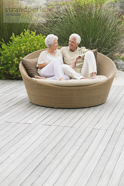 Seniorenpaar auf einer Weidencouch sitzend