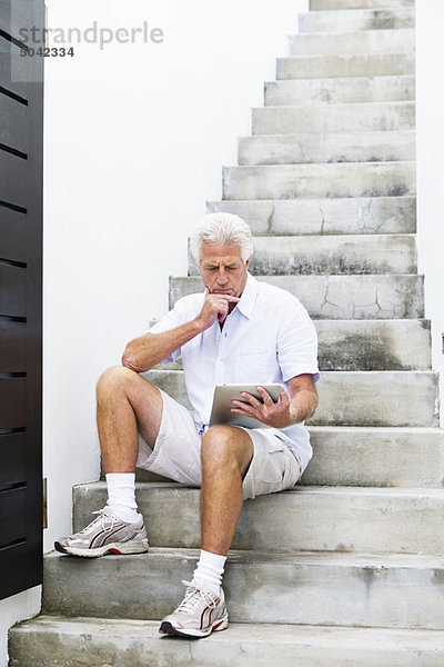 Älterer Mann beim Betrachten des digitalen Tabletts
