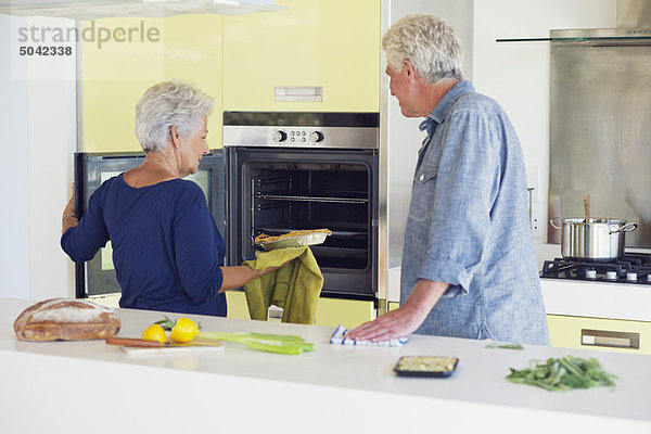 Seniorenpaar beim Backen im Ofen