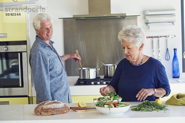 Seniorenpaar bei der Zubereitung von Speisen in der heimischen Küche
