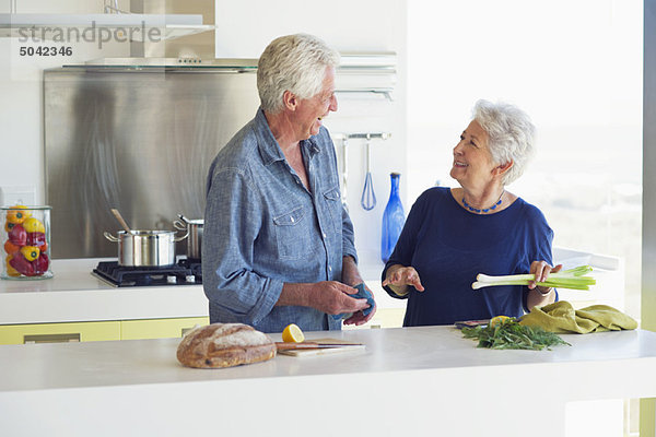 Glückliches Seniorenpaar bei der Zubereitung von Speisen in der heimischen Küche