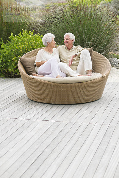 Seniorenpaar auf einer Weidencouch sitzend