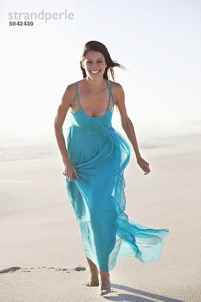 Lächelnde Frau beim Laufen am Strand