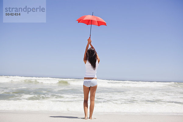 Rückansicht einer Frau mit Regenschirm am Strand