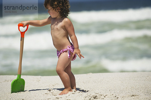 Mädchen beim Spielen mit einer Sandschaufel am Strand