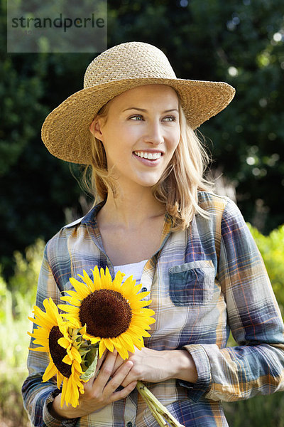 Glückliche junge Frau mit Sonnenblumen auf dem Feld