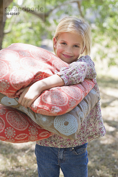 Porträt eines lächelnden Mädchens mit Kissen im Freien