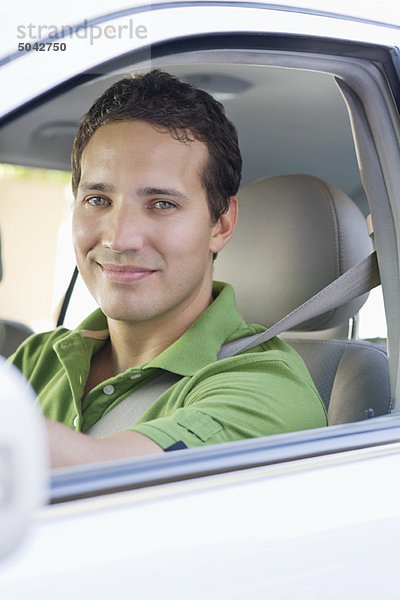 Porträt eines lächelnden mittleren Erwachsenen  der ein Auto fährt.