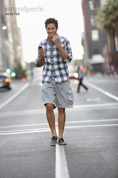 Ein Mann  der auf dem Handy spricht  während er auf der Straße unterwegs ist.