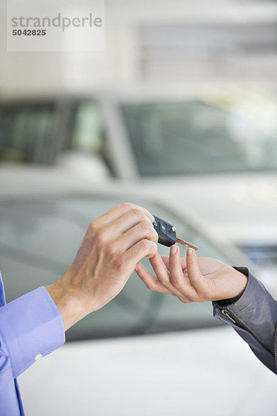 Verkäufer übergibt Autoschlüssel an Frau