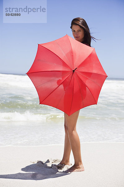 Porträt einer Frau mit Regenschirm am Strand