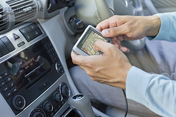 Nahaufnahme der menschlichen Hand mittels GPS-Navigationssystem im Auto