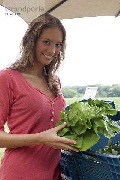 Junge Frau mit Salatkopf