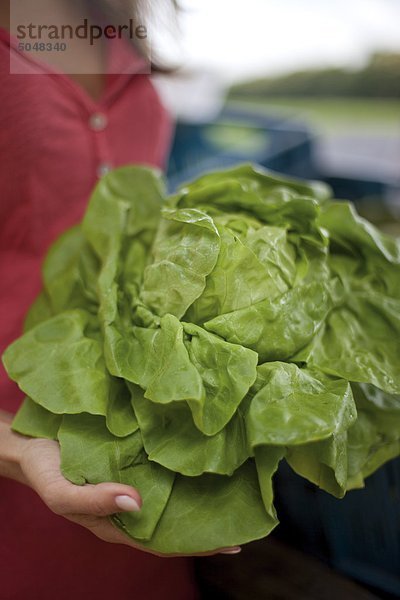 Junge Frau mit Salatkopf