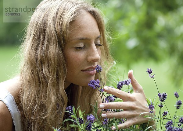 Junge Frau riecht an Blumen