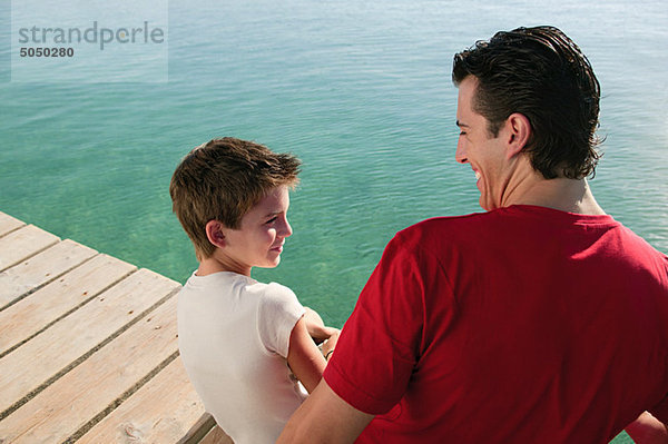 Vater und Sohn auf einem Steg am Meer