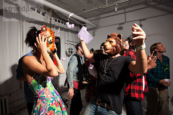 Menschen mit Löwen- und Tigermasken  die auf der Party tanzen.