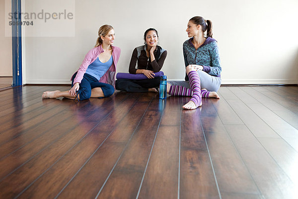 Drei Frauen sitzen auf Fitness-Studio-Boden