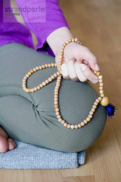 Frau kniend haltend Perlen