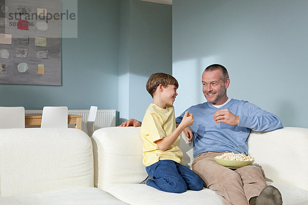 Vater und Sohn beim Fernsehen beim Popcornessen