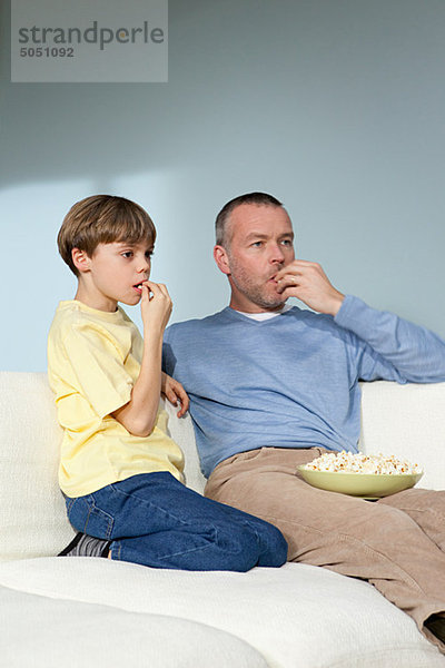 Vater und Sohn beim Fernsehen beim Popcornessen
