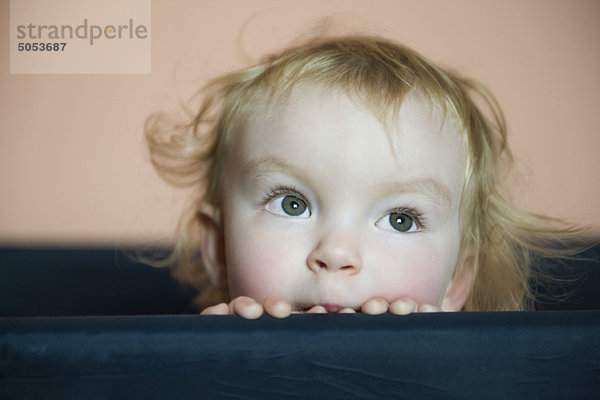 Baby Mädchen schaut über die Seite der Krippe  Portrait