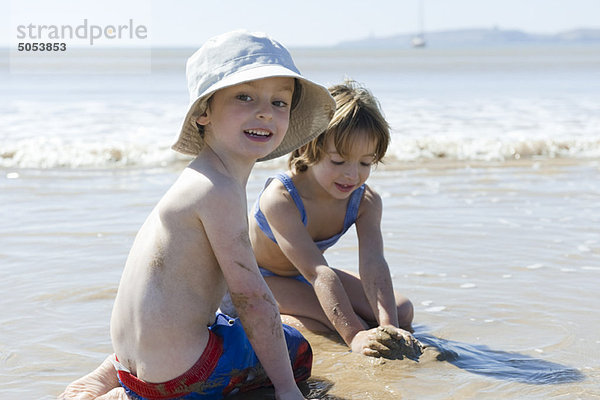 Junge spielt mit Schwester am Strand