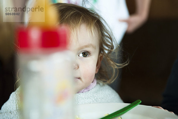 Kleinkind Mädchen am Tisch  Babyflasche im Vordergrund