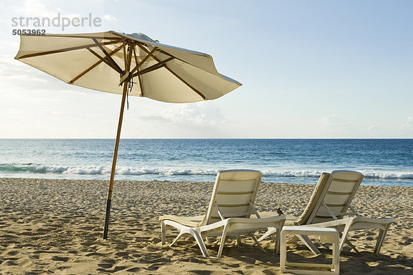 Sonnenschirm und Liegestühle am Strand